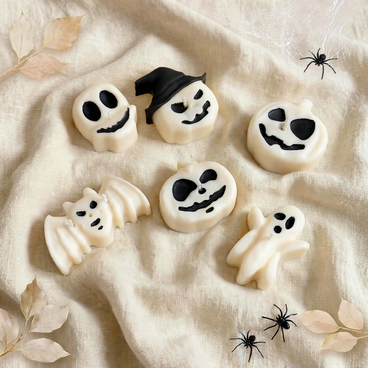 Midnight Coven handmade Halloween candle set by Glowbaltic, six hand-poured white rapeseed wax candles with black details: skull, pumpkin with a black witch's hat, two jack-o'-lanterns, bat and ghost